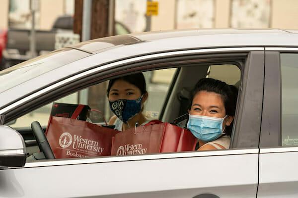 New physician assistant students receive their medical equipment during a curbside distribution in the parking lot behind the WesternU Bookstore. New physician assistant students and roommates Claudia Moroney, right and Erin Tsuji, show off their new medical equipment.