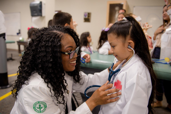 A medical student and young girl with a stethoscope.