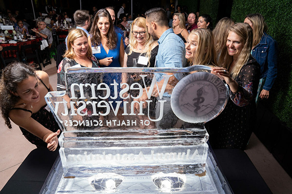 A group of people standing around a large ice sculpture.