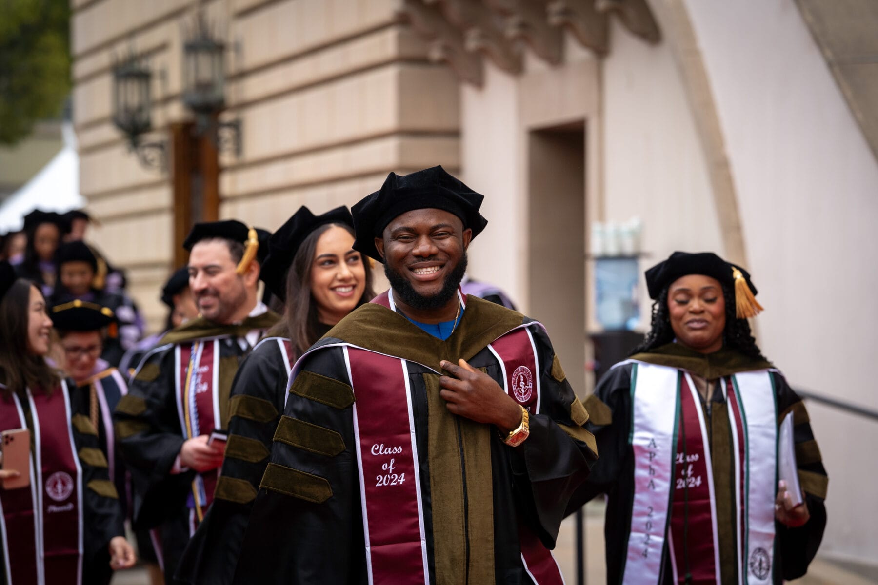 Male smiling wearing a graduation robe and hood