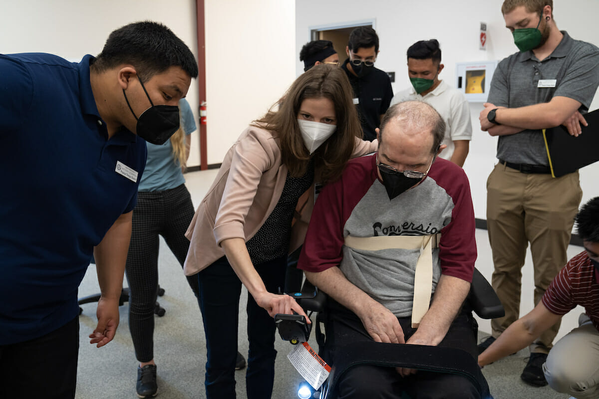 CHS-Northwest physical therapy students get hands-on experience in the Practical Applications Lab with a volunteer patient and his power chair. Assistant Professor Kendra Cherry-Allen, PT, DPT, PhD. was teaching and supervising. (Jeff malet, WesternU) *Volunteer Randy was cleared to be photographed as he signed an authorization for use of image, voice and likeness.