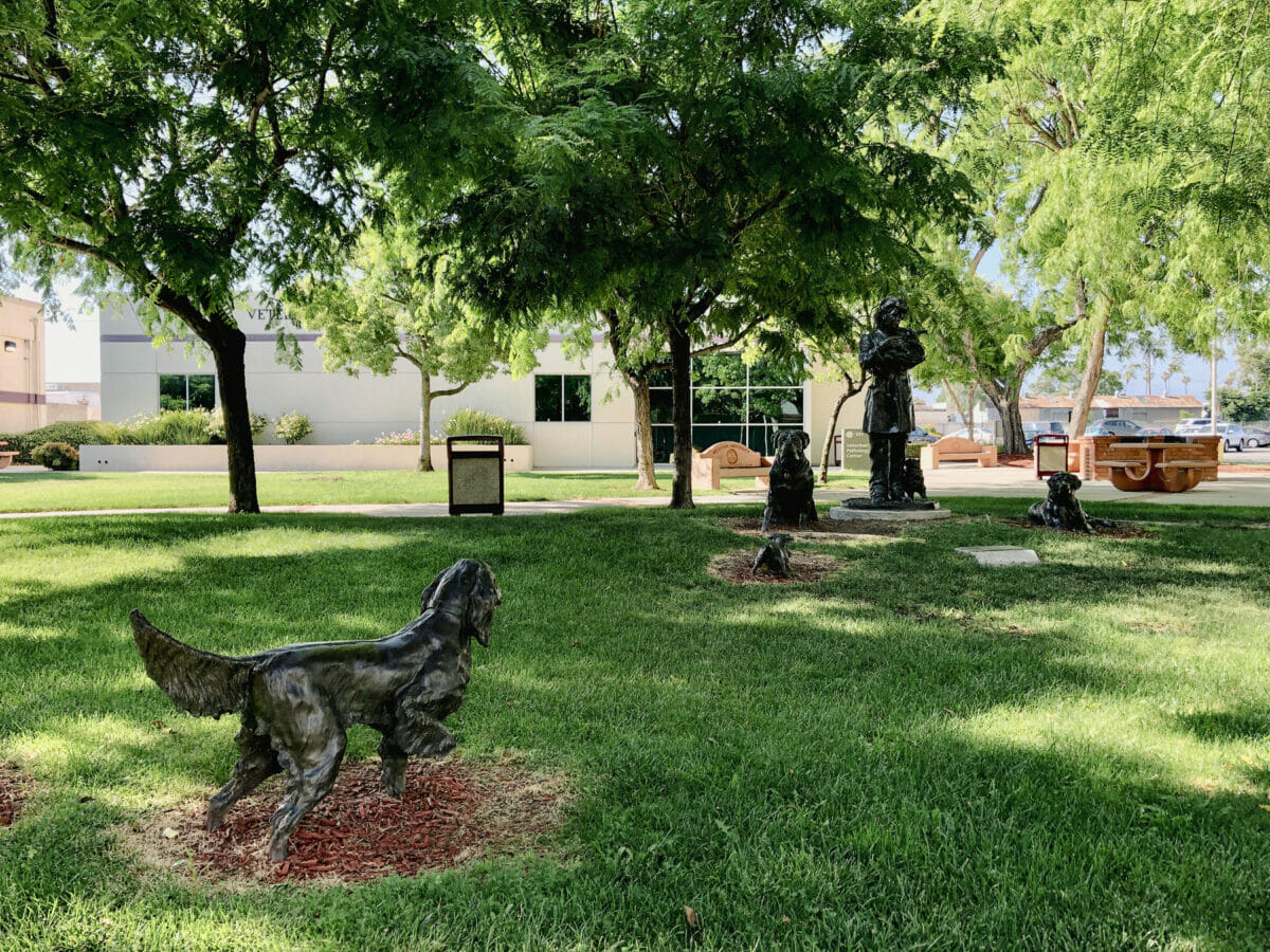 a group of statues of dogs in a grassy area.