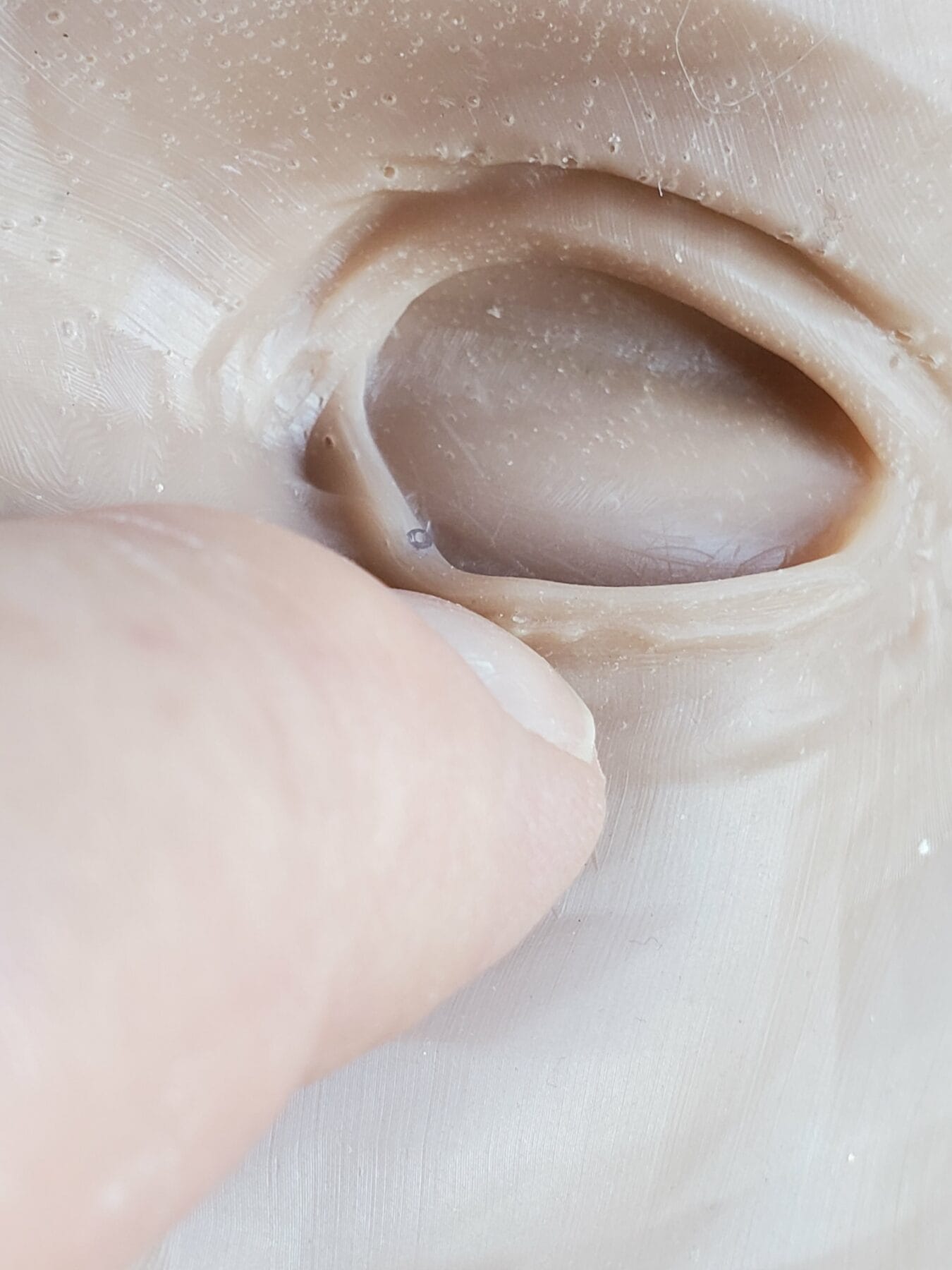 A finger presses into a hollow rubbery surface, creating an indentation.