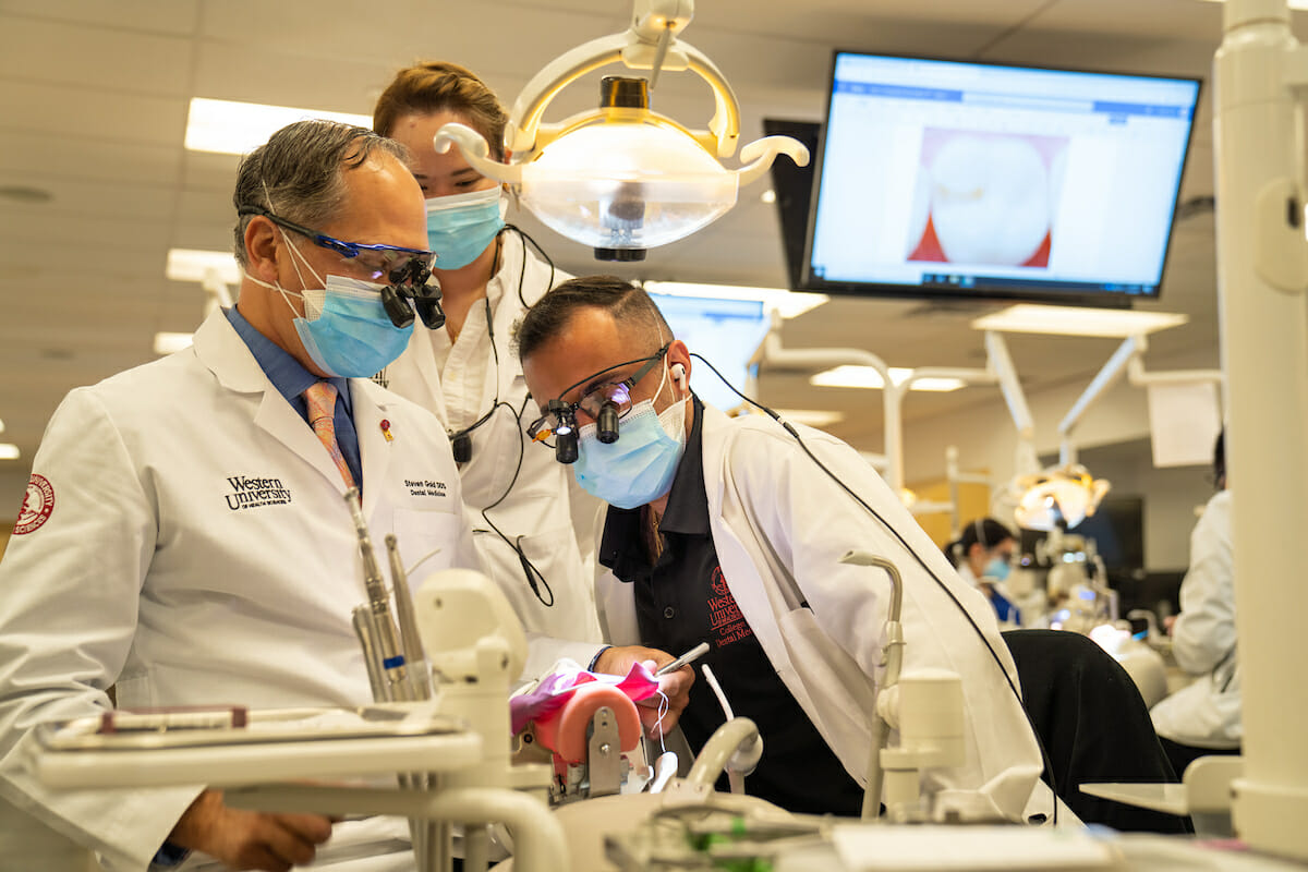 College of Dental Medicine Assistant Professsor Steven Gold, DDS, provides hand-on training to students Emmie Ho and Sean Zendedel in the Dental Sim Lab