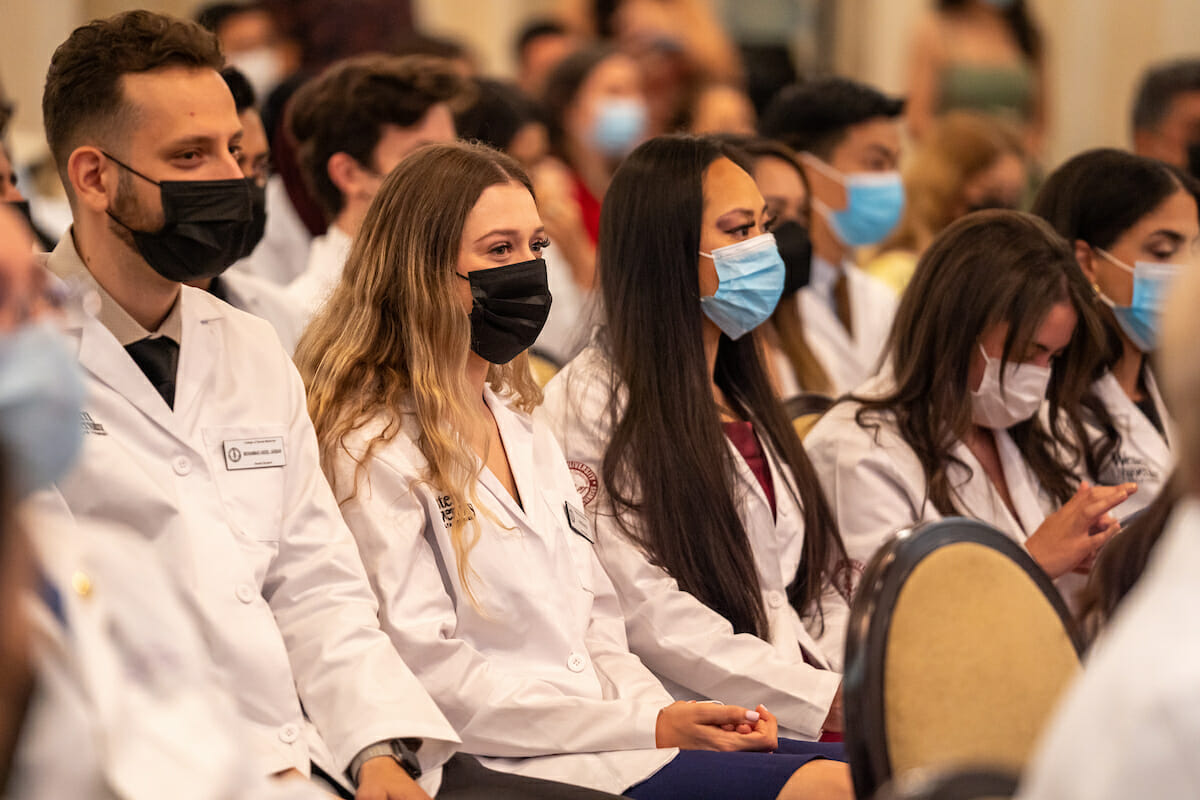 Five seated students in white coat ceremony for dental college