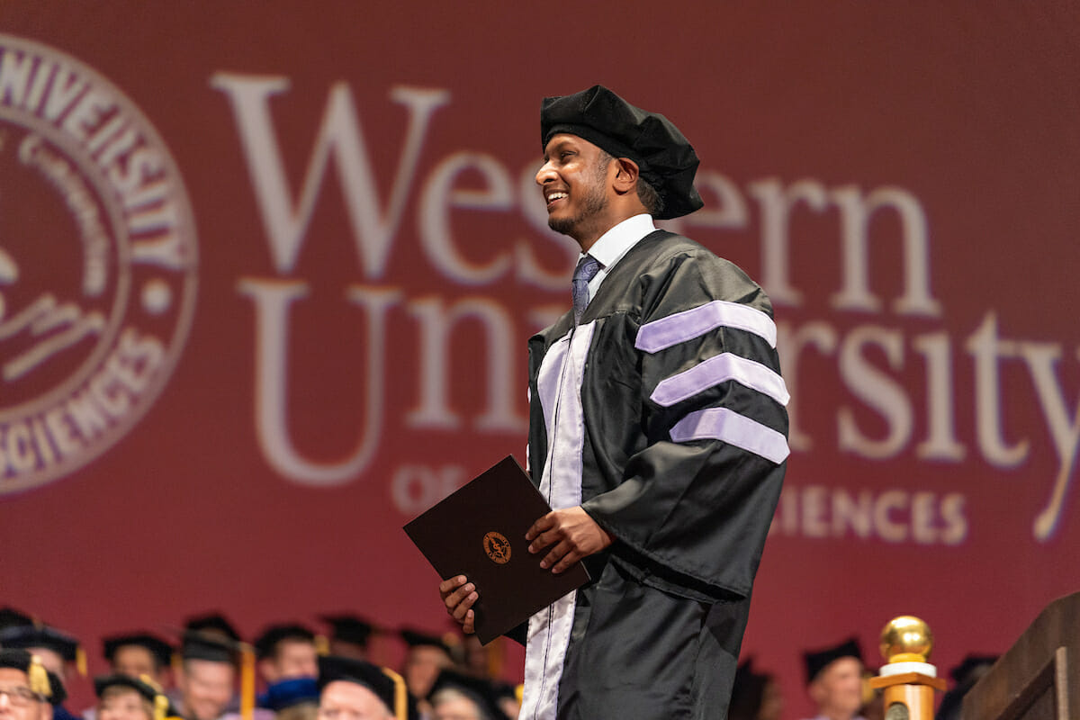 Graduate of dental program walking across stage during commencement