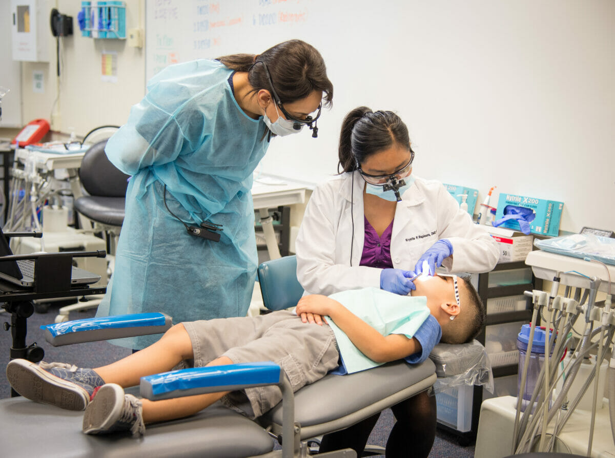 Dental student and faculty working on child patient in dental care clinic