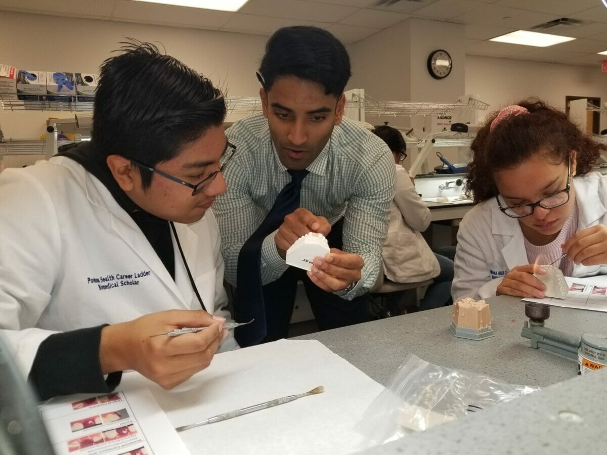 Two students and faculty working with dental molds