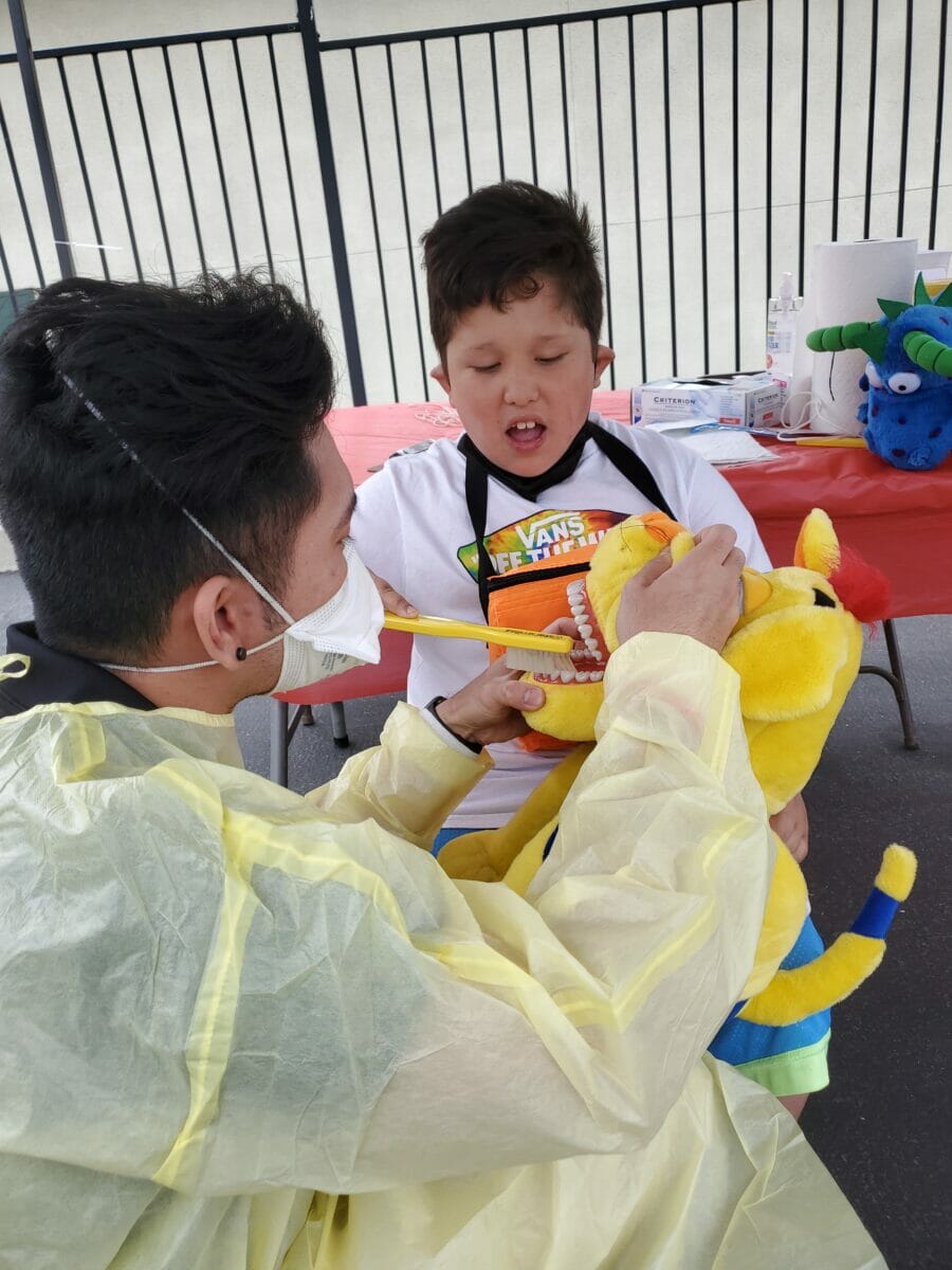 Student volunteering in special olympics demonstrating how to brush teeth