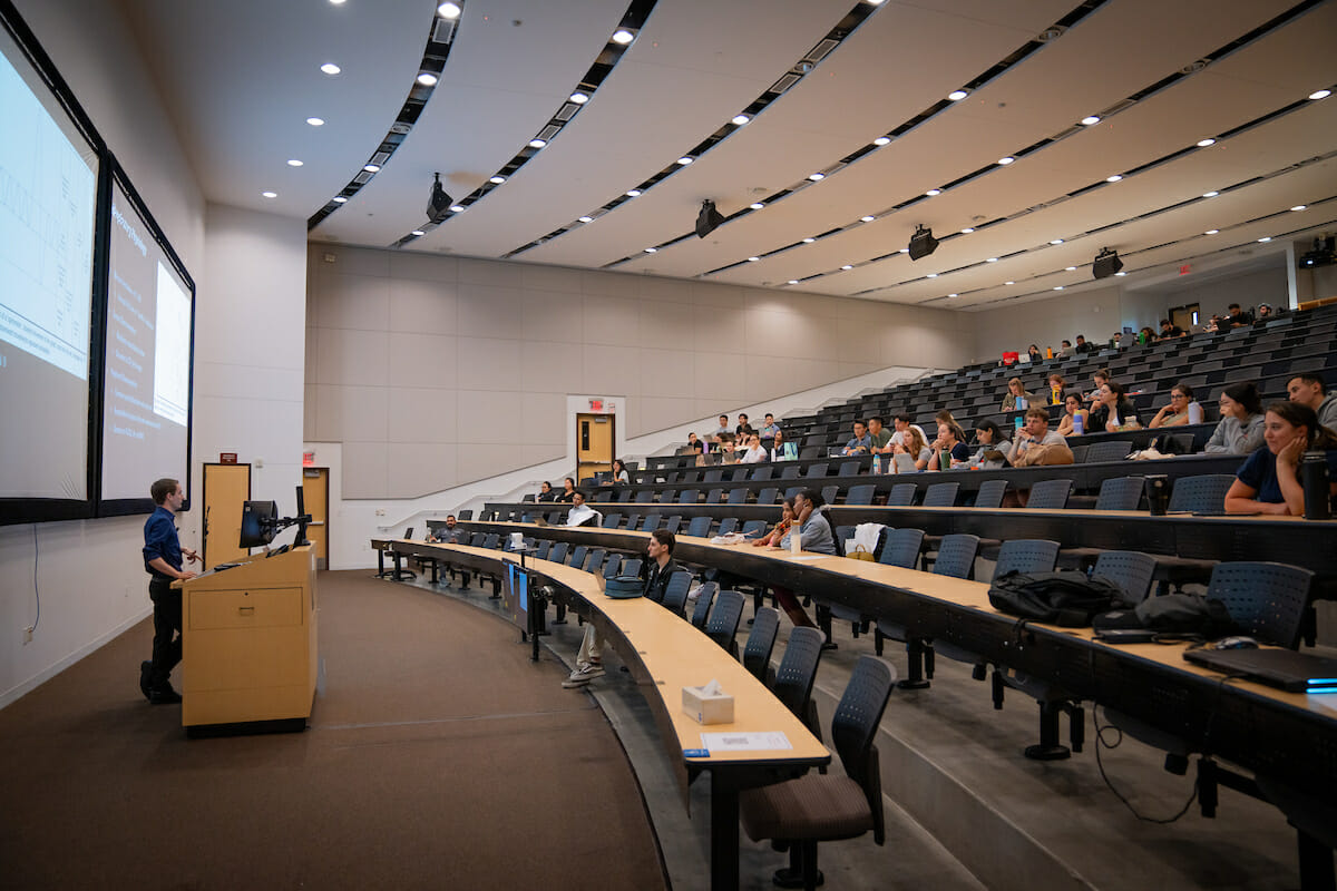 Large lecture hall, many people.