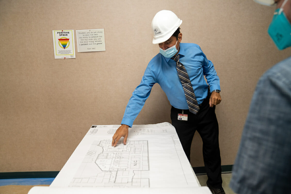 A man wearing a hard hat and hard hat looking at blueprints.