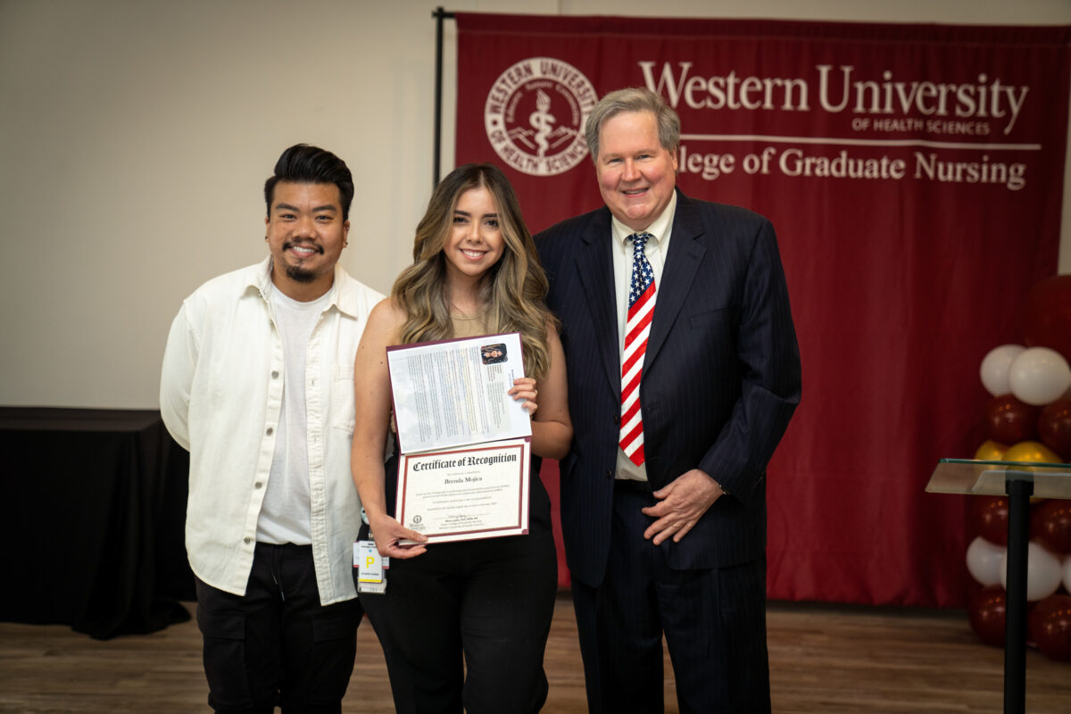 Three people standing next to each other holding a certificate.