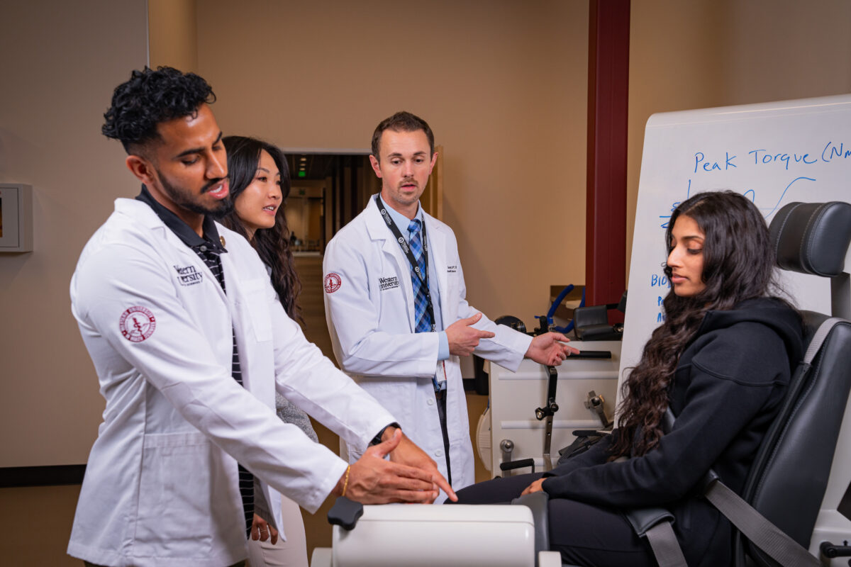 A group of doctors in lab coats working with a patient in a chair.