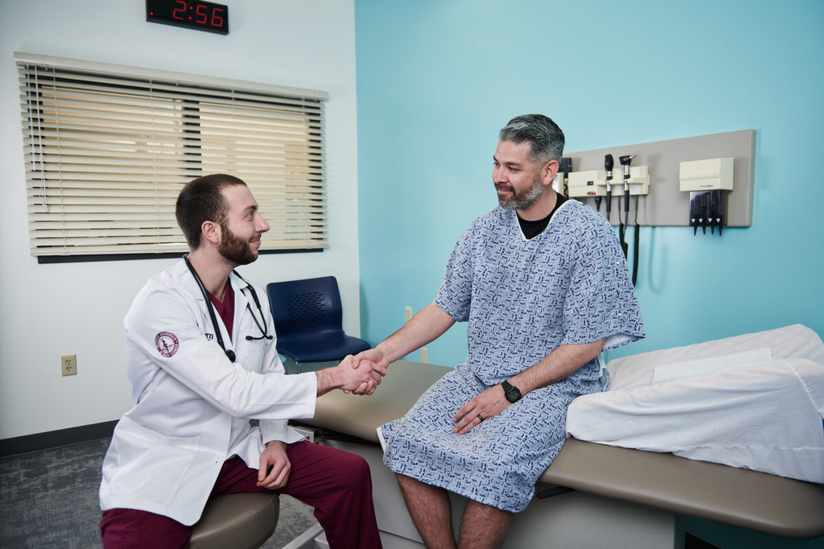 Two doctors shaking hands in a hospital room.