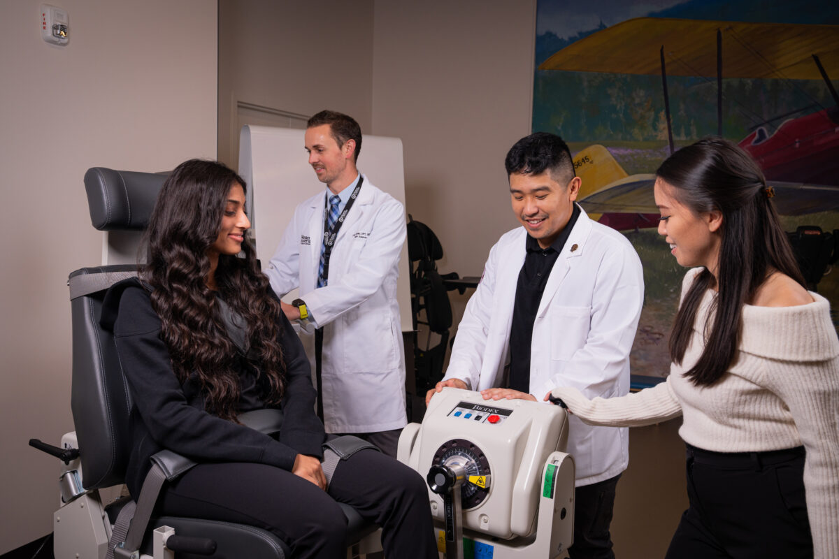 A group of people are sitting in a chair with a machine in front of them.