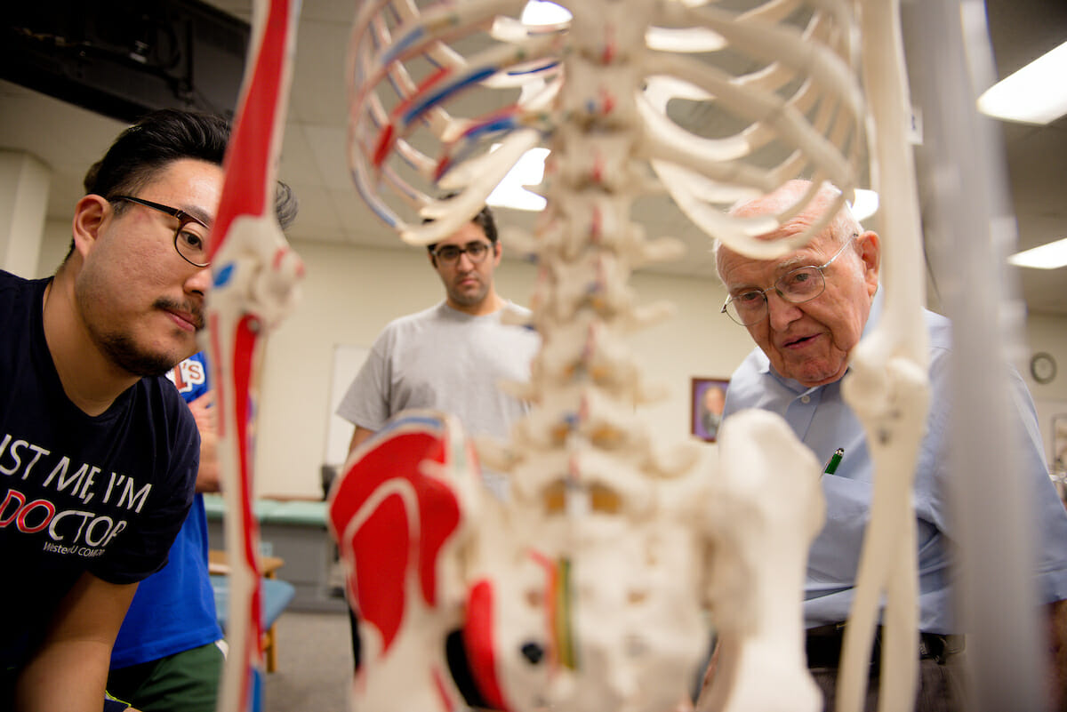 A group of people looking at a skeleton in a lab.