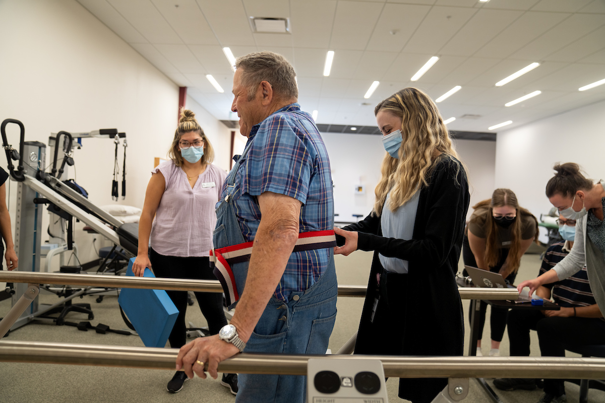 A group of people standing in a gym with a person wearing a mask.