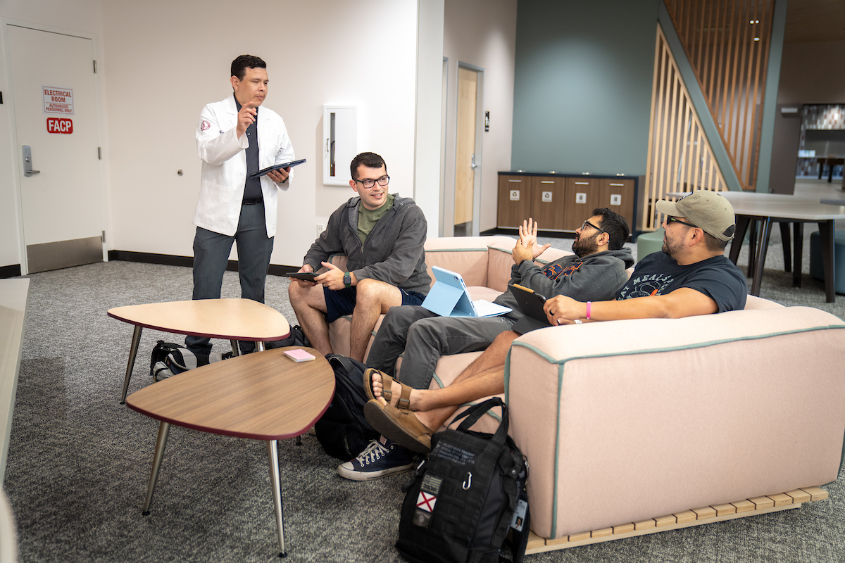 A group of people sitting around a couch in a room.