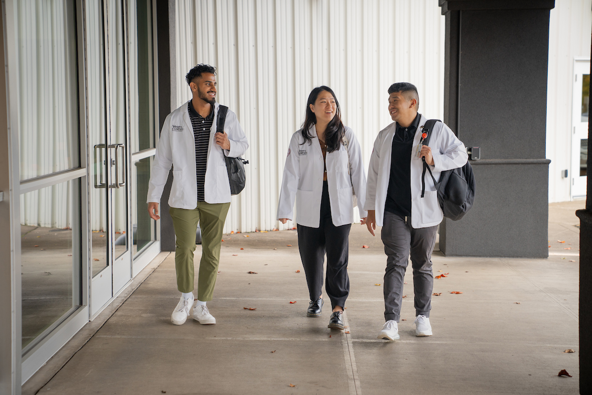 A group of people in lab coats walking down a hallway.