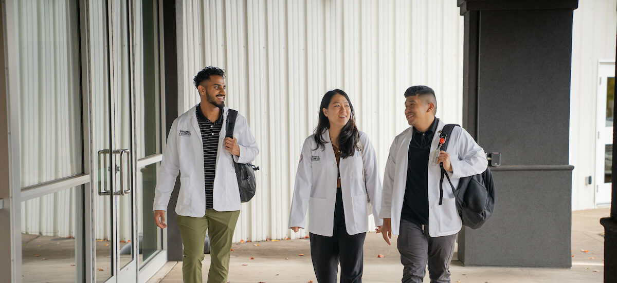 A group of people in lab coats walking down a hallway.