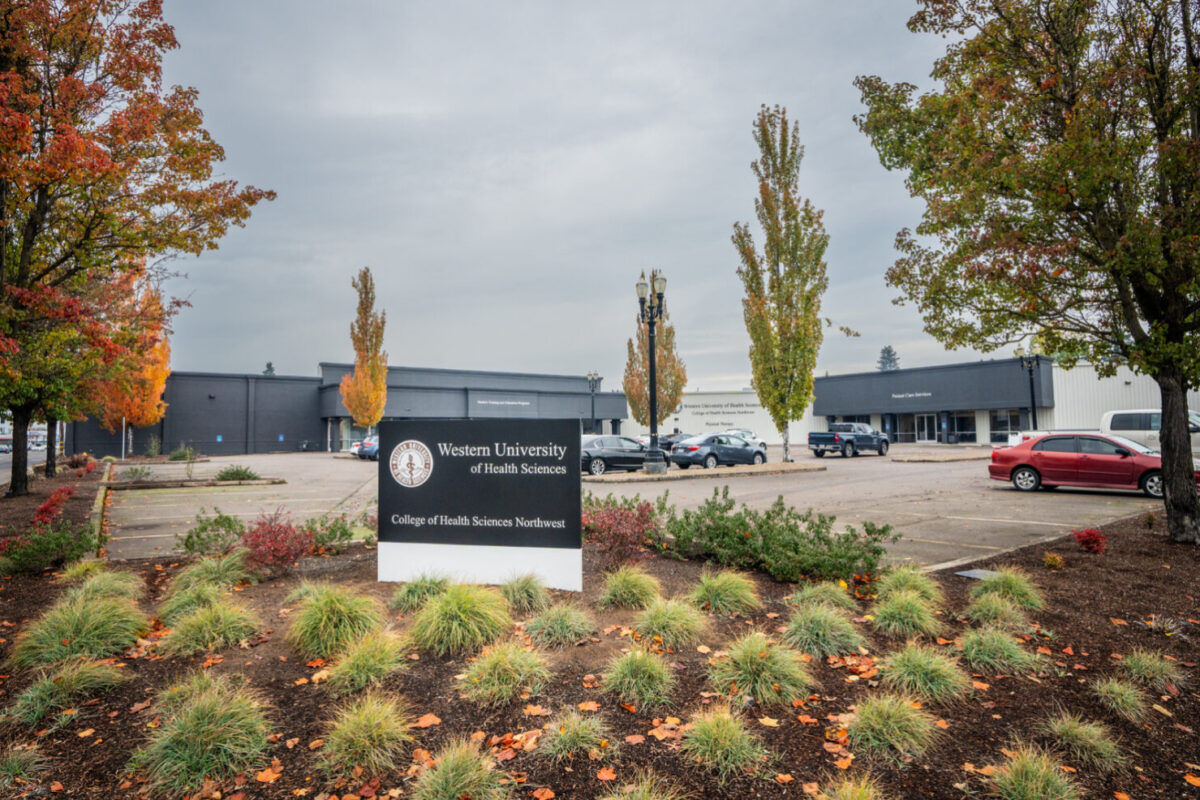 A sign in front of a building with trees in the background.