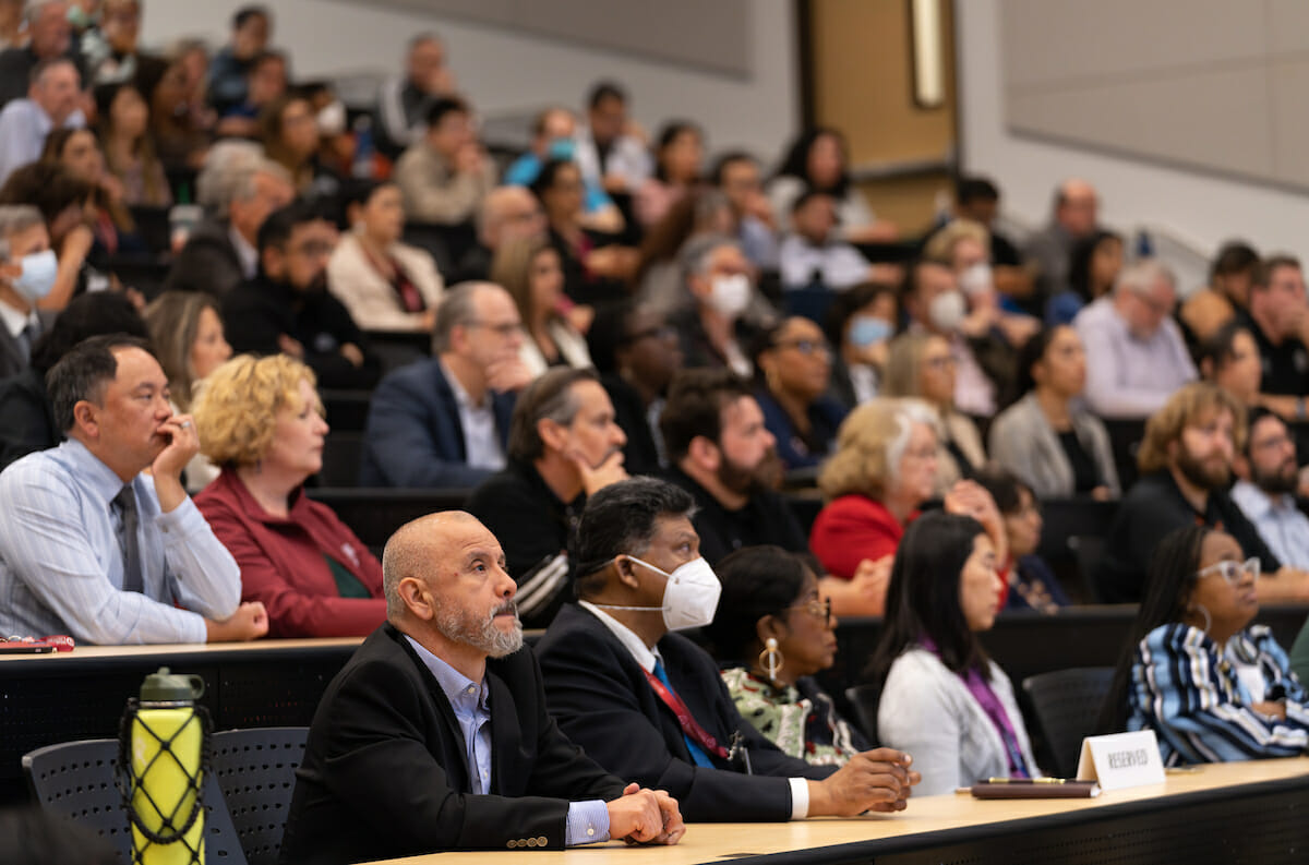 group, lecture hall. Revised description: A group seated before a lecture hall.