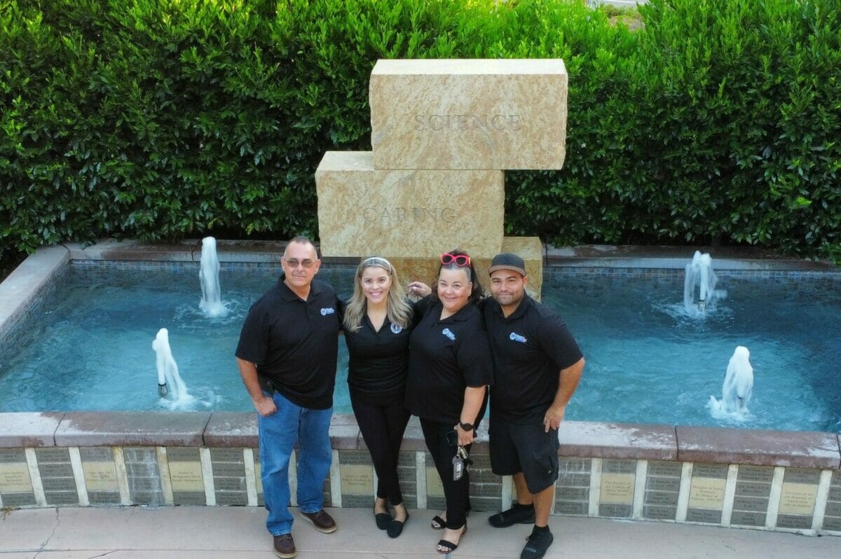 Four people posing in front of a fountain.