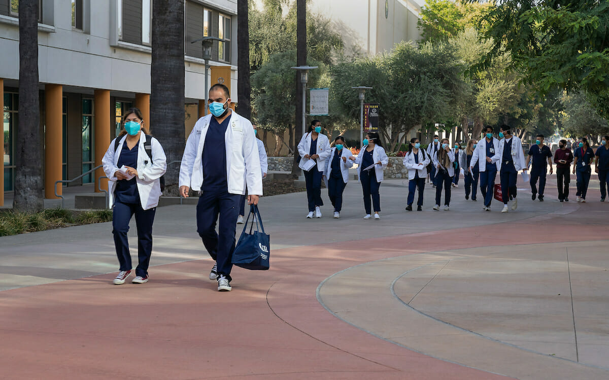 A group of medical students walking down a sidewalk.