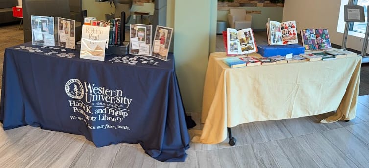 Two display tables with books and informational materials at Western University’s Harriet and Phillip Pumerantz Library, one table with a dark cloth and another with a light cloth.