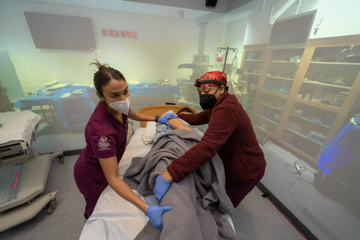 Two nursing students turning manikin in simulation rom