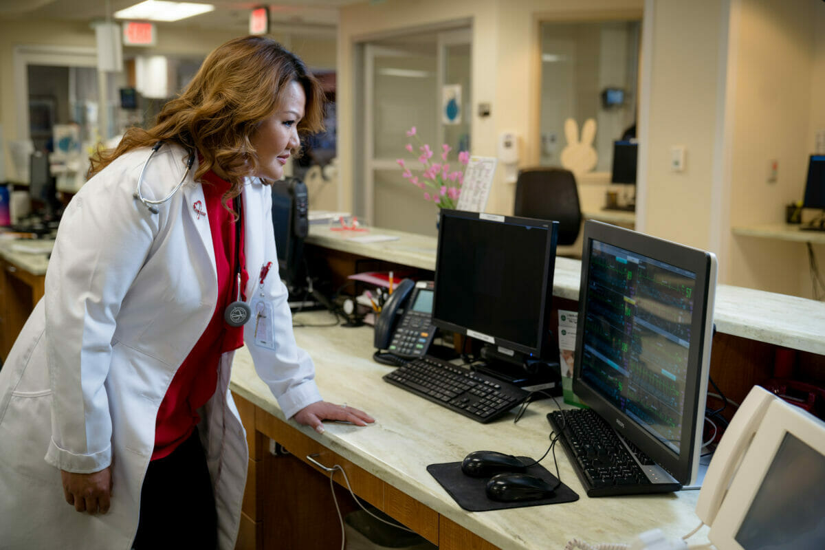Female doctor at counter looking at computer screen