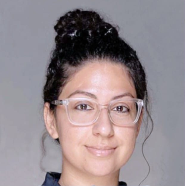 Female. Brunette. Smiling. Wearing glasses.
