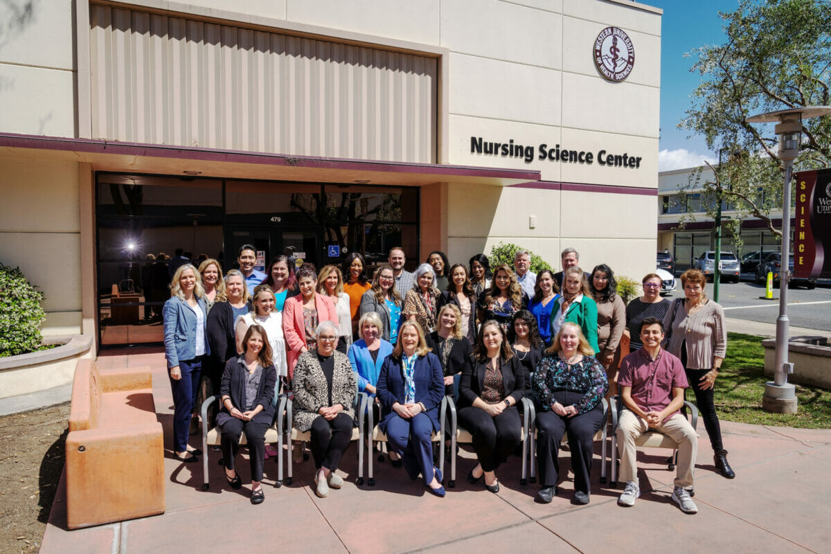 Nursing faculty and staff seated outdoors in front of Nursing Science Center