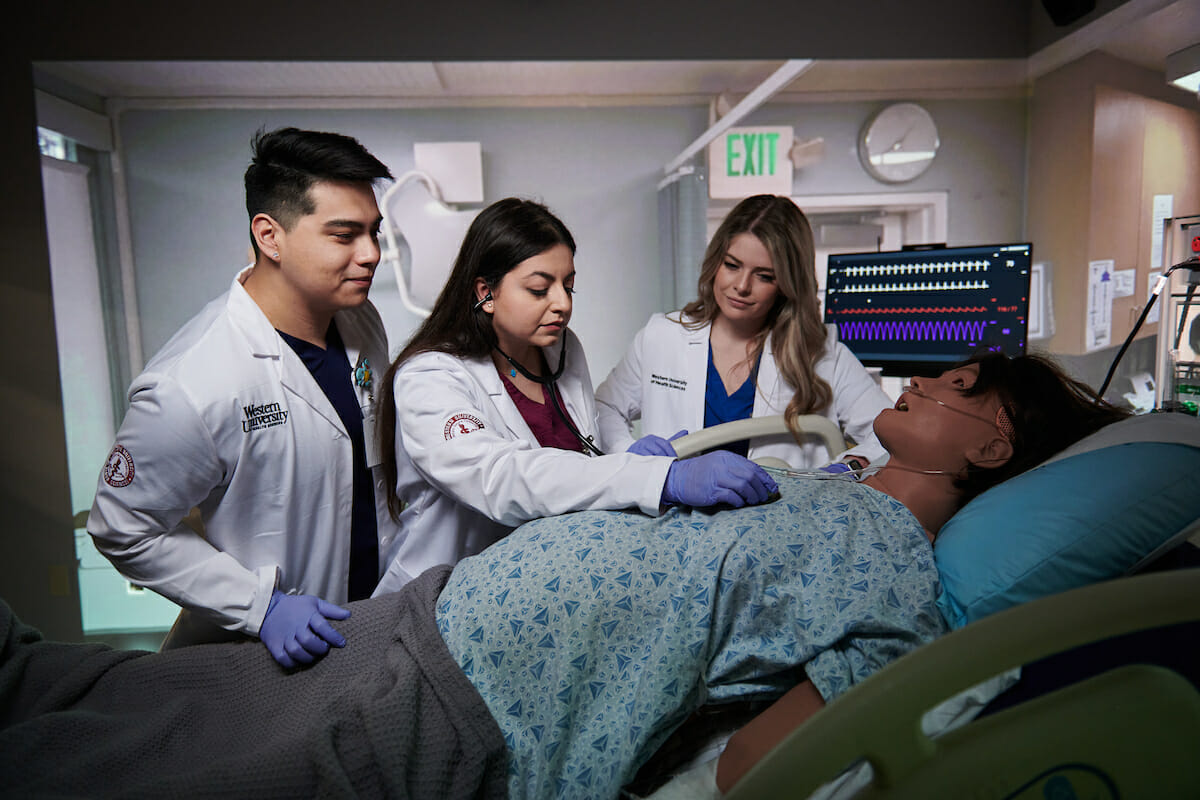 a group of students and a doll in a hospital bed