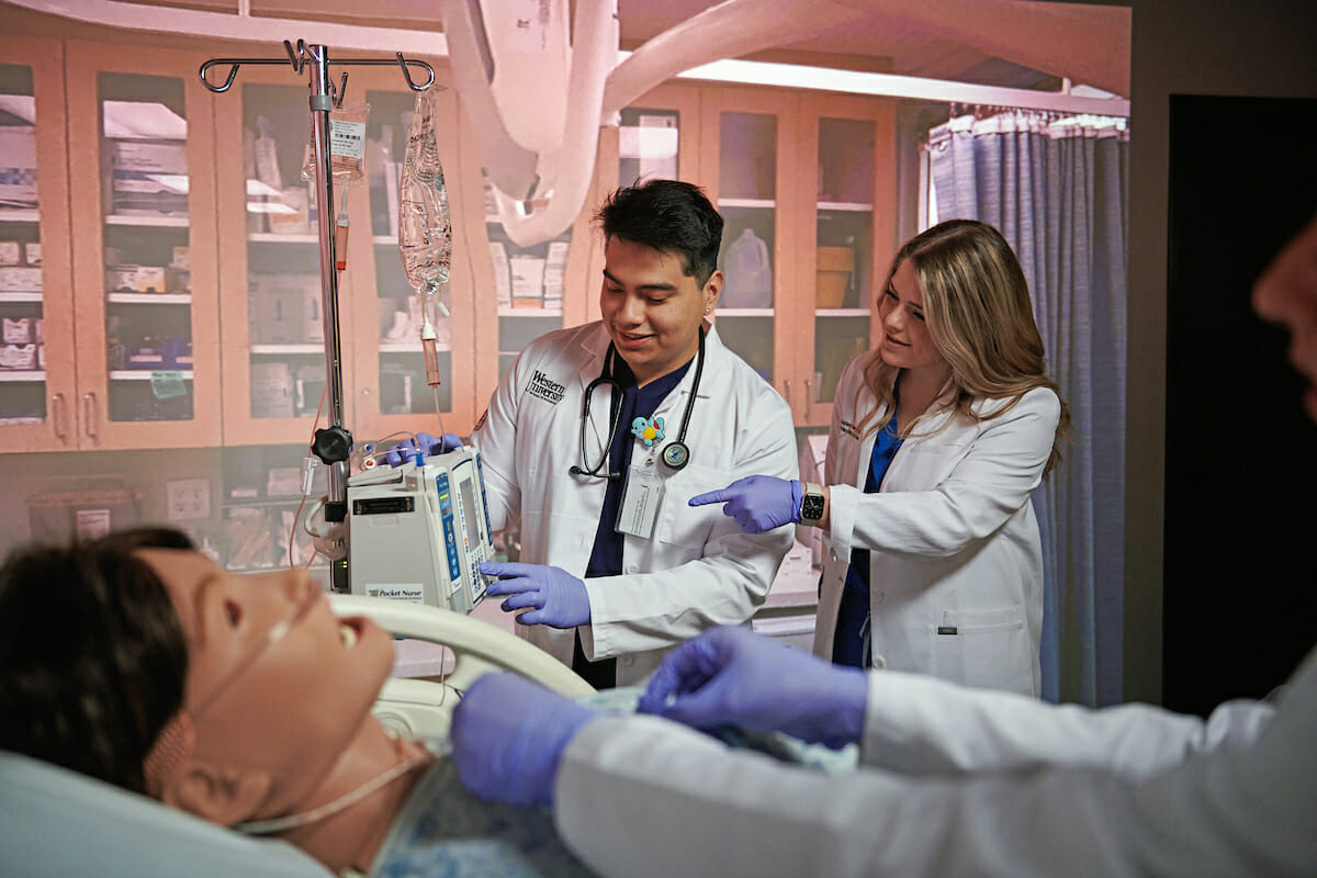 a group of students and a doll in a hospital bed