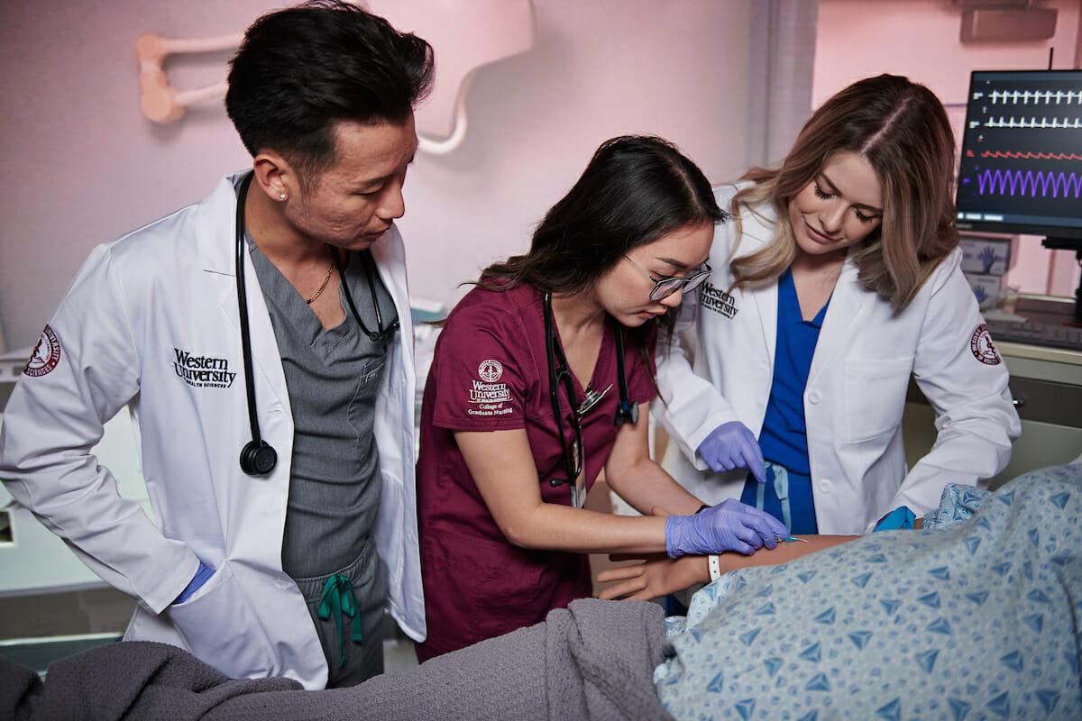 a group of medical personnel examine a dummy.