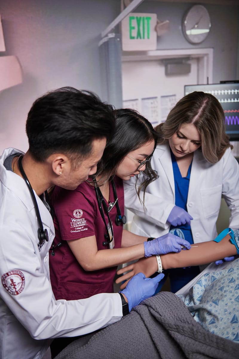 Three medical students focused on a patient.