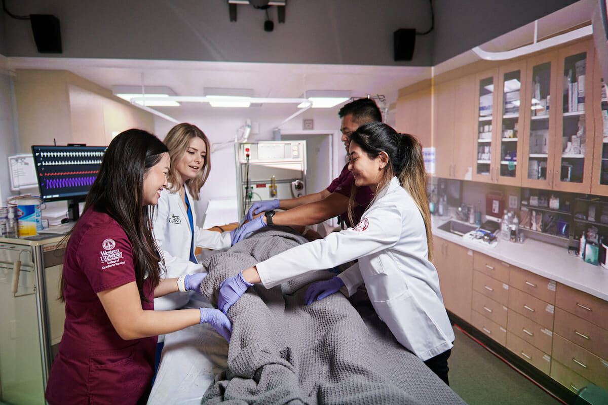 a group of medical personnel examine a dummy.