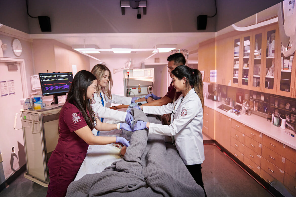 a group of medical personnel examine a dummy.