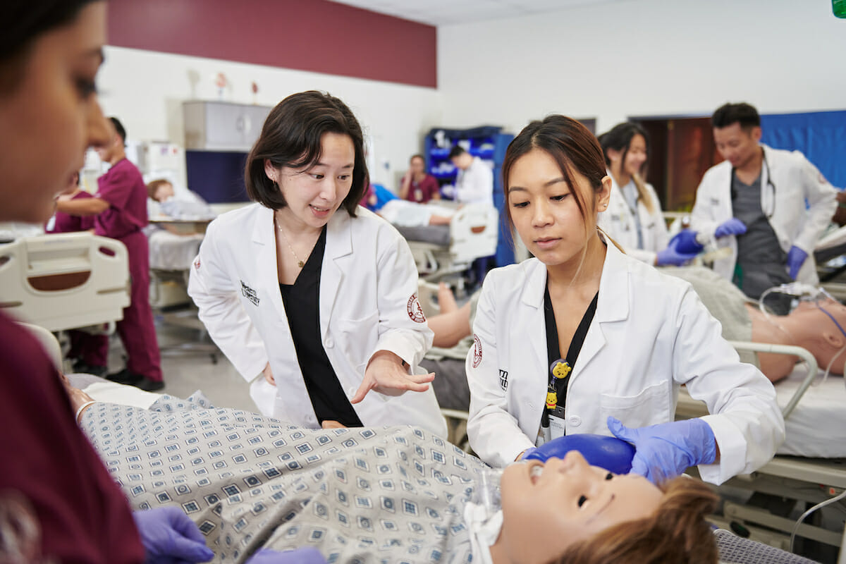 a group of medical personnel examine a dummy.