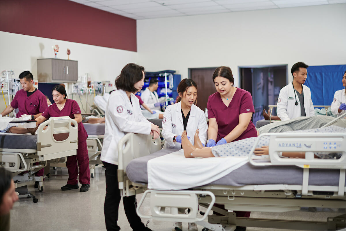 a group of medical personnel examine a dummy.