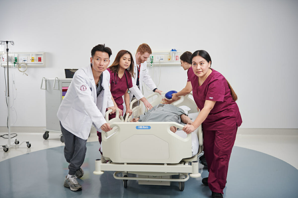 a group of medical personnel examine a dummy.