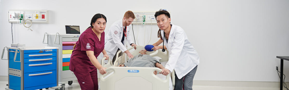 a group of medical personnel examine a dummy.