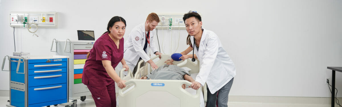 a group of medical personnel examine a dummy.