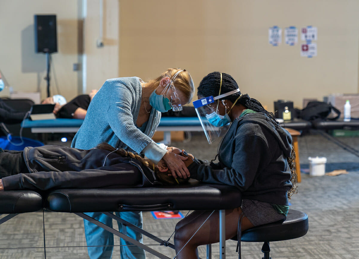 Second-year College of Osteopathic Medicine of the Pacific students gain hands-on clinical skills training at Fairplex Pomona building 8 Friday, March 5, 2021. COMP has been using the large building to give students hands-on OMM experience during the pandemic, proving a spread-out environment and protocols that students are paired together for the duration, among other rules. During this session, students gained experience doing the cranial palpatory experience. COMP student Ifeoluwa Adesina practices a cranial palpatory experience on fellow student Brianna Novak.