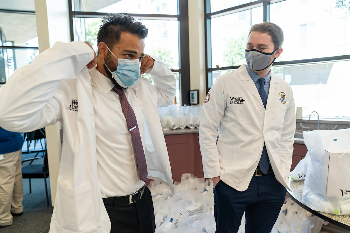 College of Osteopathic Medicine of the Pacific incoming student Nisar Sheren tries on a white coat as fellow student Ira Glassman looks on during WesternU Welcome Week day three,