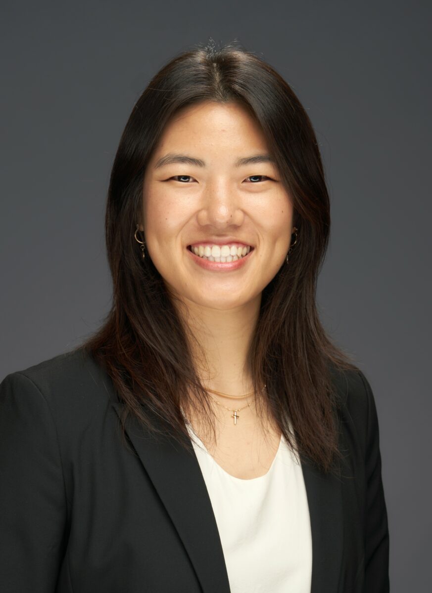 Asian woman in a business suit smiling for the camera.