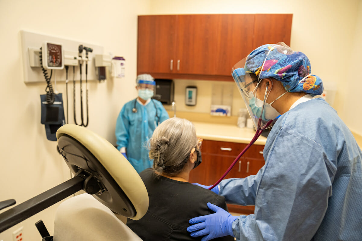 Physicina Assistant Trang Sparks and third-year COMP student Alice Wang examine a “patient” wearing proper PPE during the pandemic.. “Patient” is Margie Rivera.