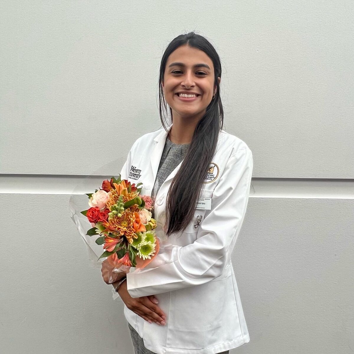 A female doctor holding a bouquet of flowers.