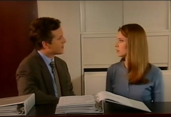 a woman talking to a man at a desk.